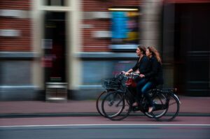 Zwei Frauen fahren nebeneinander auf einem Radweg in der Innenstadt.