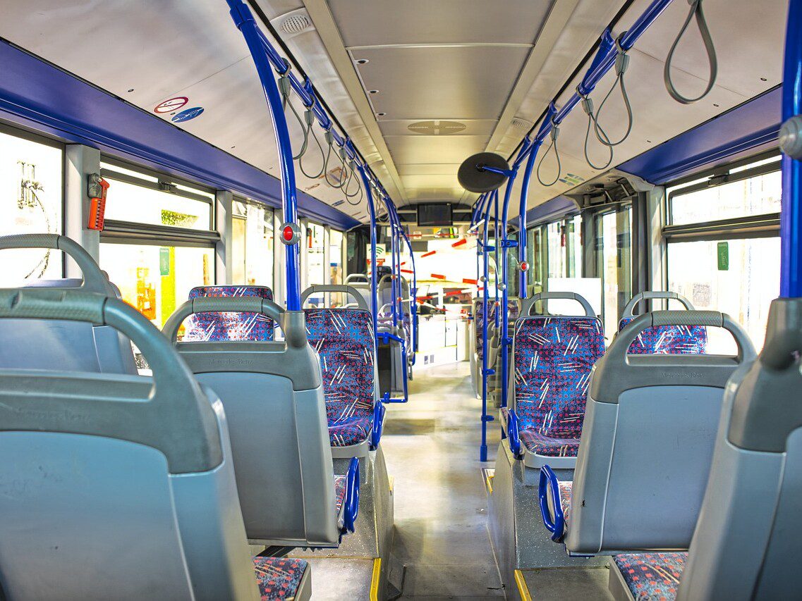 Das Innere eines Omnibusses mit Sitzplätzen und Haltegriffen.