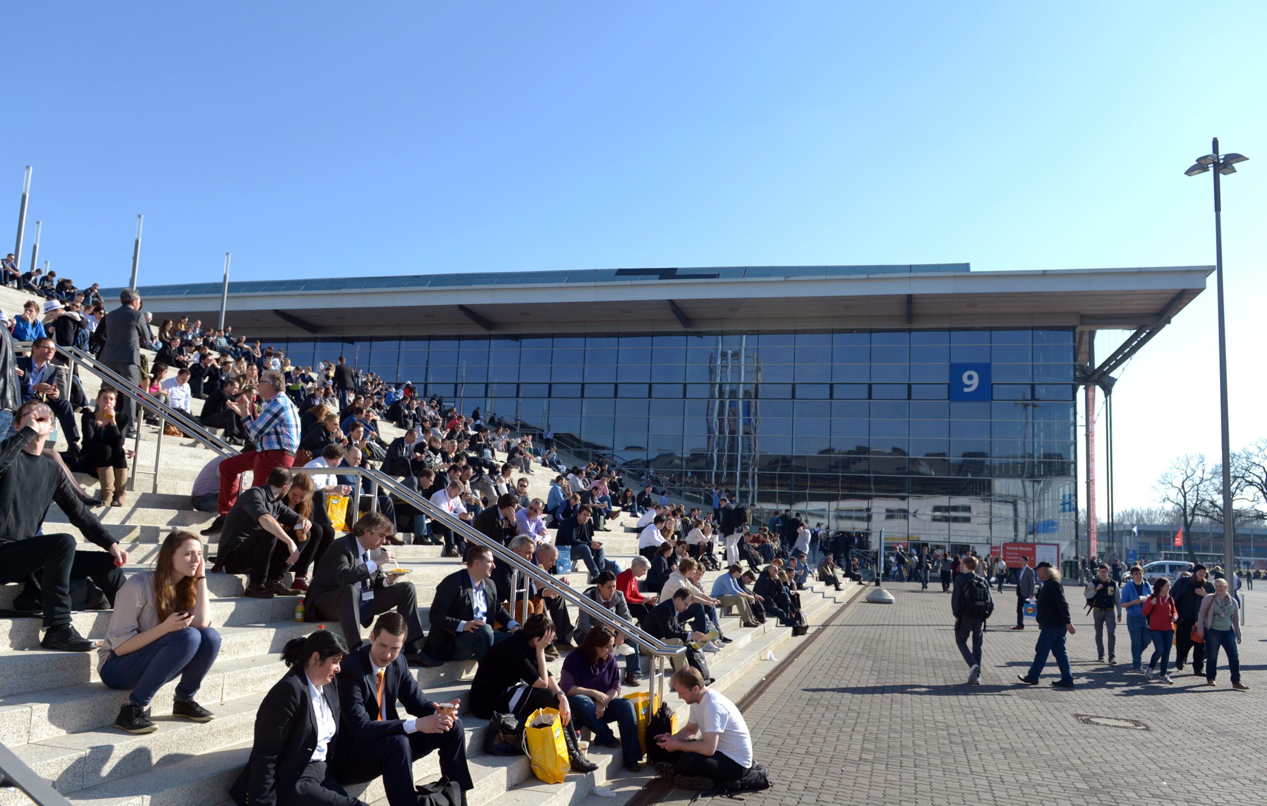 Zahlreiche Besucher sitzen auf einer großen Treppe vor der Messehalle 9 in Hannover