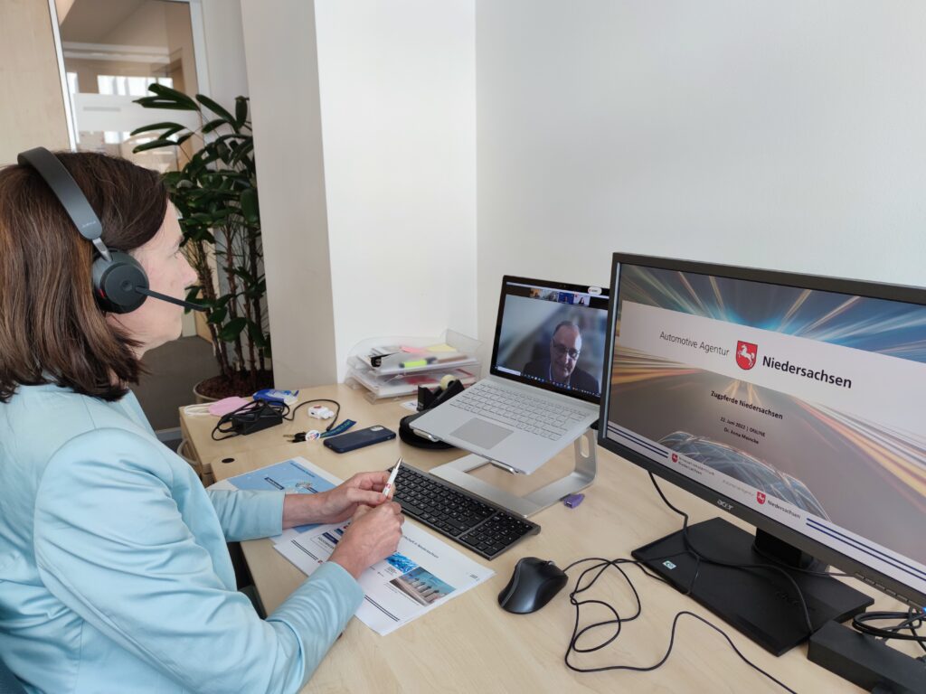 Dr. Anna Meincke, Leiterin der Automotive Agentur mit Headset an einem Schreibtisch mit zwei Bildschirmen.