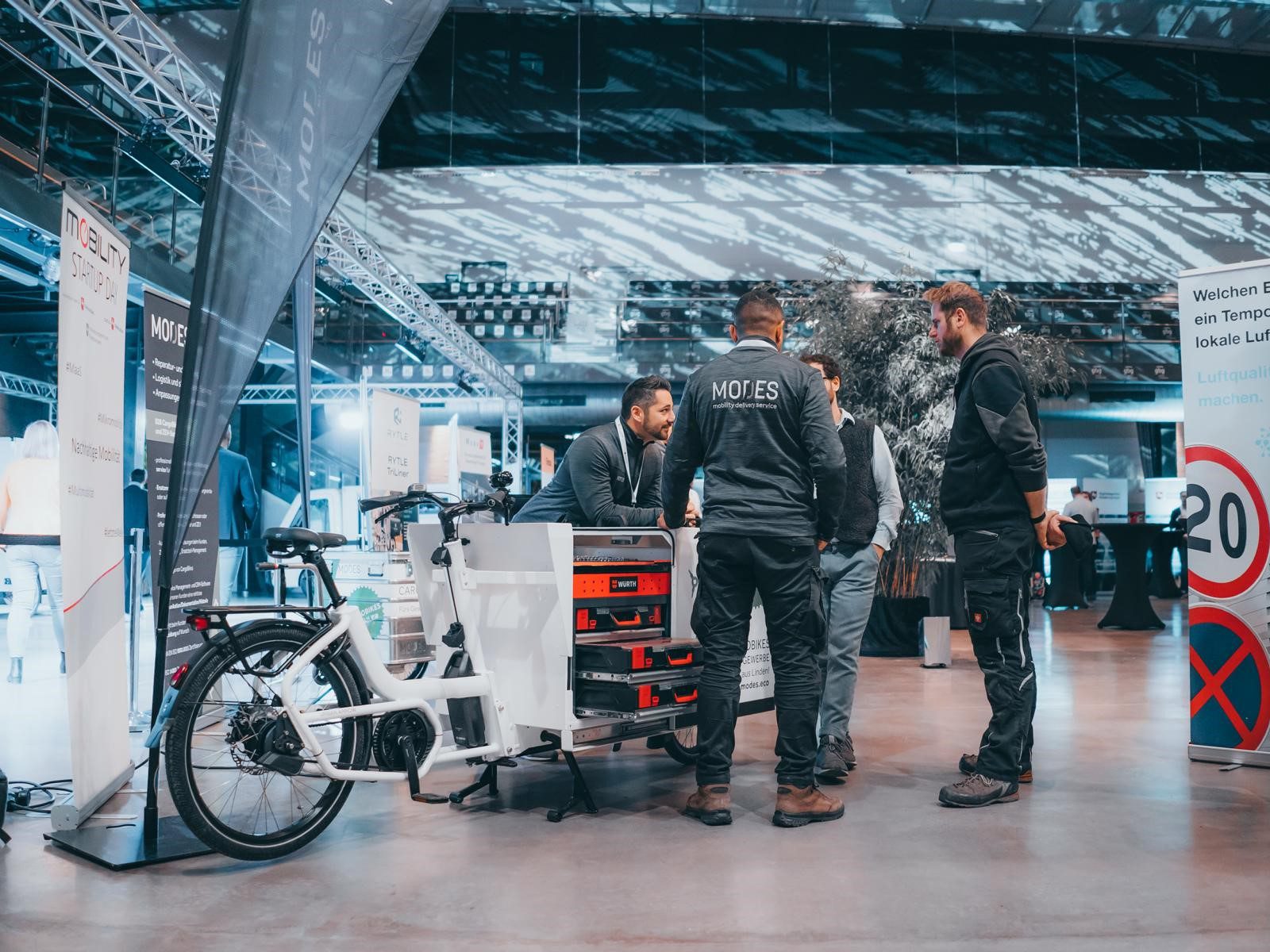 Fachgespräch am Stand vor einem E-Cargo Bike mit eingebautem Werkzeugkasten zur mobilen Wartung