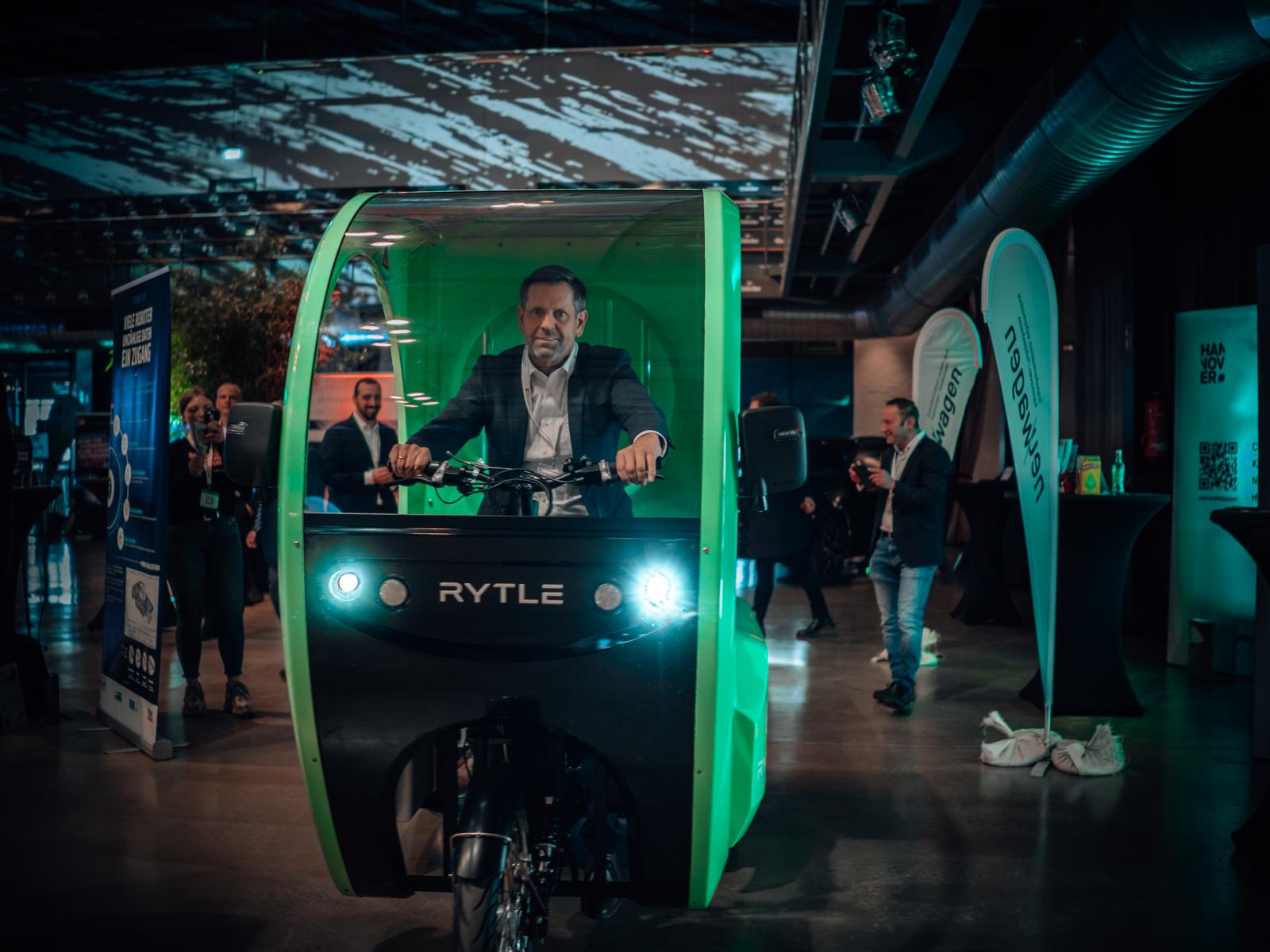 Niedersachsens Wirtschaftsminister Olaf Lies am Steuer eines grün-schwarzen E-Cargo Bikes mit abgerundeter Fahrerkabine