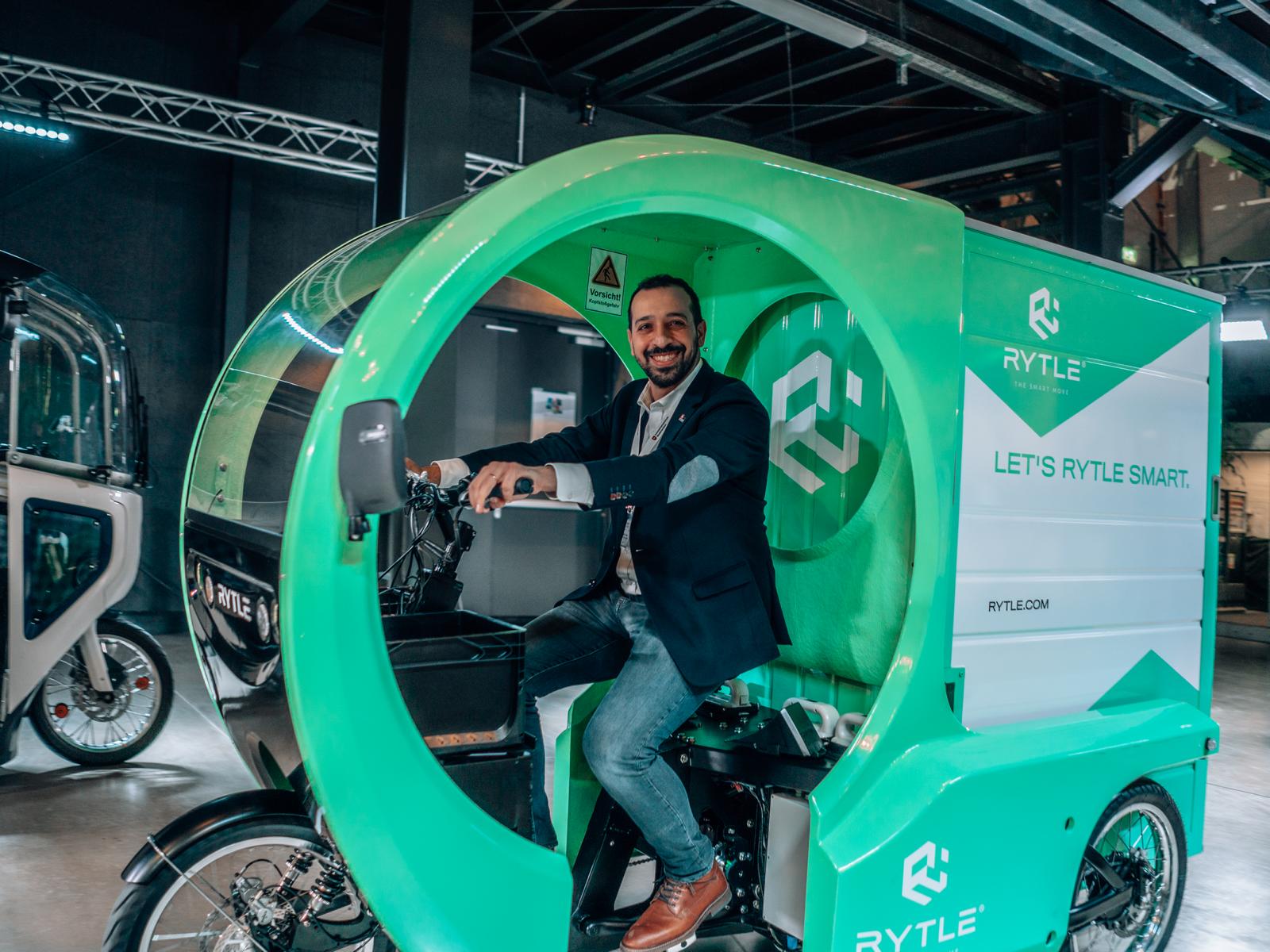 Barkin Özkaya von der Automotive Agentur am Steuer eines grünen E-Cargo Bikes