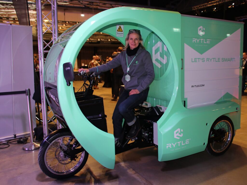 Angela Drexl, Marketingmanagerin der Firma Rytle in der Fahrerkabine eines grünen E-Lastenfahrrads.