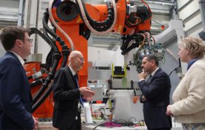 Niedersachsens Wirtschaftsminister Olaf Lies und zwei weitere Besucher bekommen vor einem Roboter etwas erklärt.