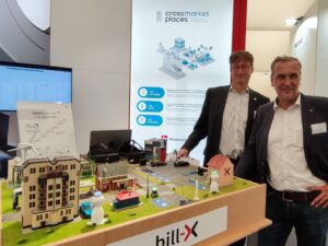 Kai Schwermann und Carsten Müller präsentieren auf einem Messestand ein Modell einer smarten City.