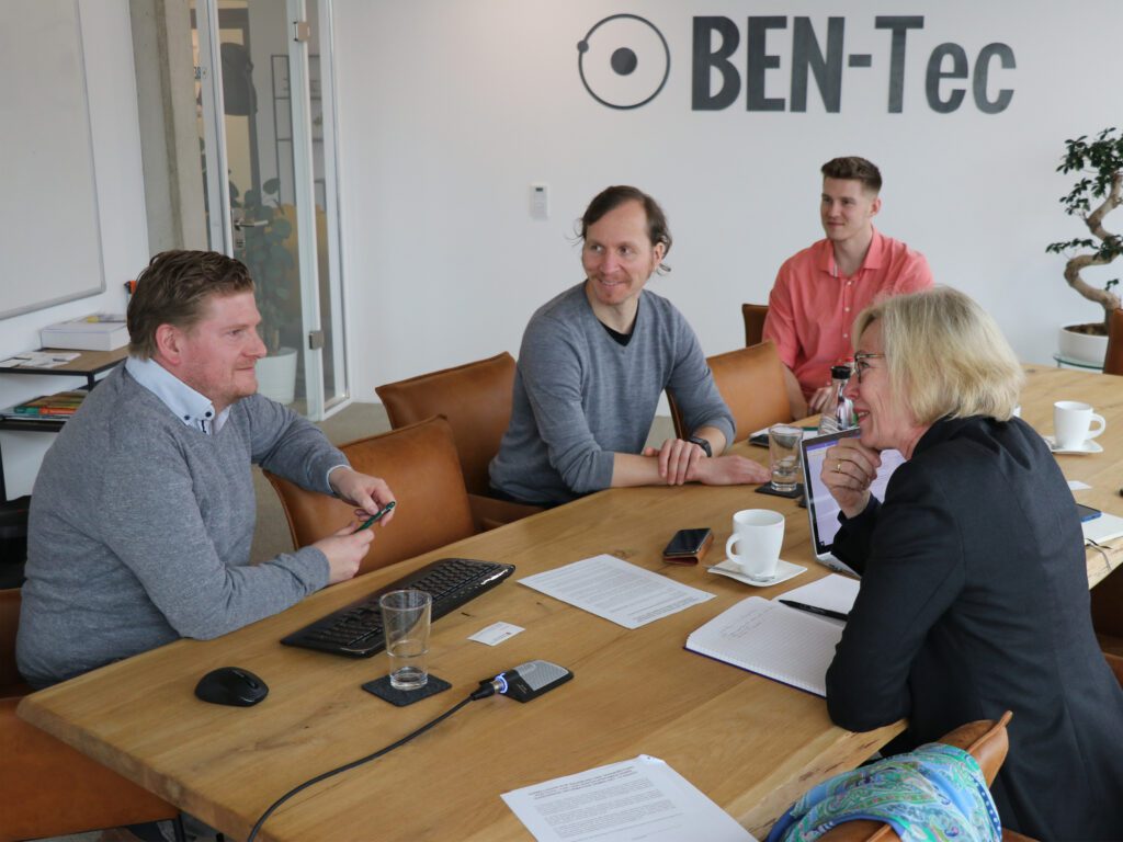 Die Vertreter der Firma BEN-Tec im Gespräch mit Gunda Fahrenkrog an einem Holztisch.