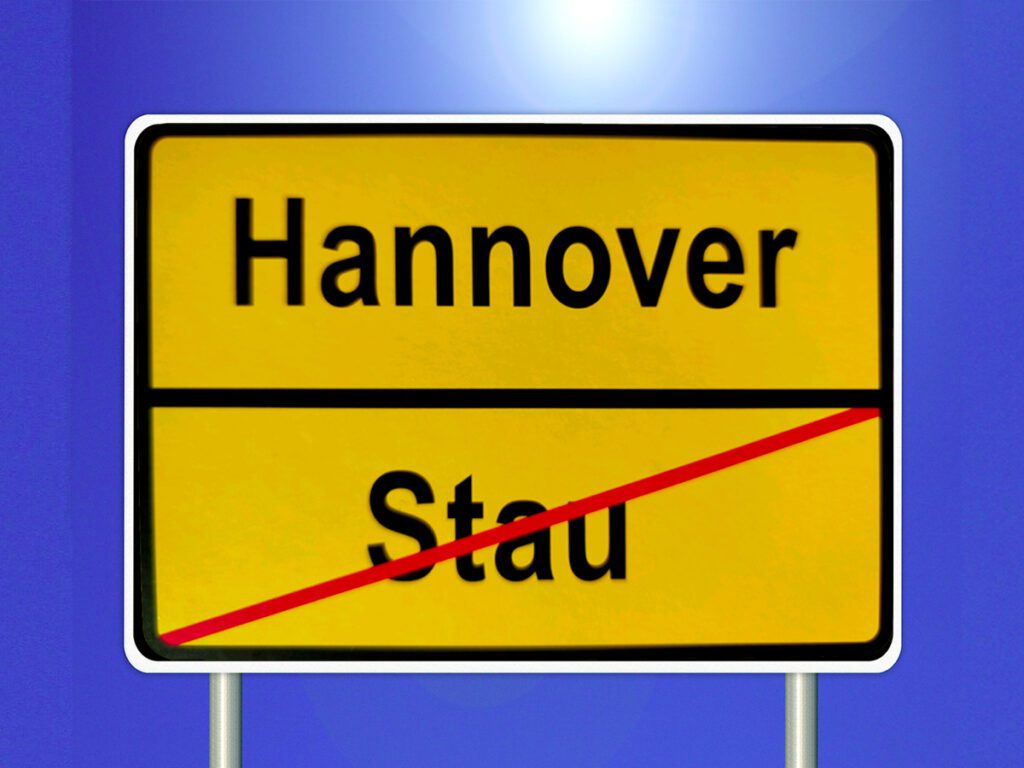 Ein gelbes Ortsausgangsschild: oben Hannover, unten das Wort Stau durchgestichen,