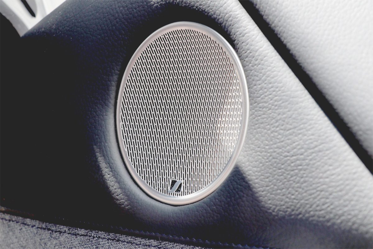 Ein runder, silberner Sennheiser-Lautsprecher in einer Autotür.