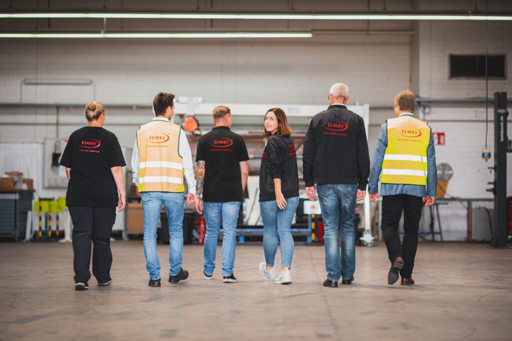 Eine Gruppe von Menschen mit Clavey-Shirts geht in eine Werkstatt.